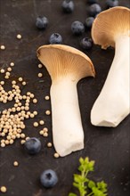 King Oyster mushrooms or Eringi (Pleurotus eryngii) on black concrete background with blueberry,