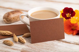 Brown paper business card mockup with orange nasturtium flower and cup of coffee on white wooden