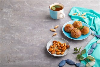 Homemade traditional turkish dessert sekerpare with almonds and honey, cup of green tea on gray