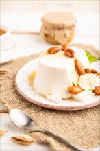 Ricotta cheese with honey and almonds on white wooden background and linen textile. side view,