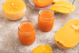 Baby puree with fruits mix, pumpkin, persimmon, mango infant formula in glass jar on brown concrete