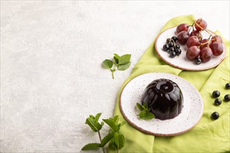 Black currant and grapes jelly on gray concrete background and green linen textile. side view, copy