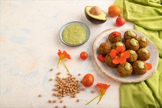 Falafel with guacamole on white concrete background and green linen textile. Side view, copy space