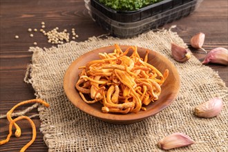 Fresh Cordyceps militaris mushrooms on brown wooden background with microgreen, herbs and spices.