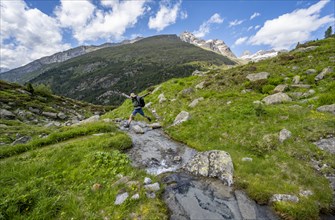 Mountaineer jumping over a mountain stream, Berliner Hoehenweg, Zillertal Alps, Tyrol, Austria,
