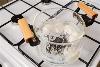 Overhead view of transparent glass saucepan with boiling eggs on a gas stove