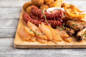 Set of snacks: sausages, fried potatoes, meat balls, dumplings, basturma on a cutting board on a