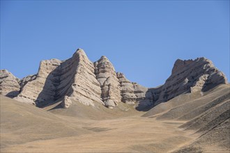 Mountain landscape with steep rocks, eroded rock formations between yellow hills, near Baetov,