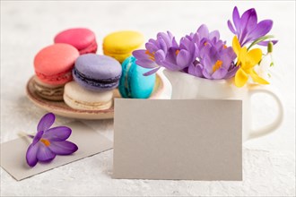 Gray paper business card mockup with spring snowdrop crocus flowers and multicolored macaroons on