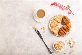 Homemade waffle with peanut butter and cup of coffee on a gray concrete background. top view, flat