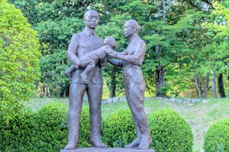 Bronze statue of Japanese man, woman and child in nature park. Artist unknown