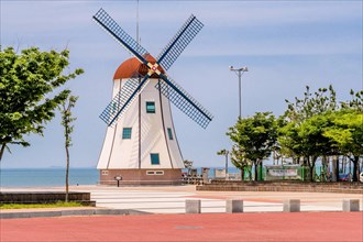 Windmill at seaside park with cloud streaked blue sky in background in South Korea