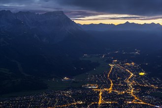 Town at night with lights in front of mountains, Garmisch-Partenkirchen, left Zugspitze,