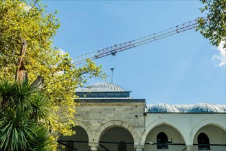 Crane arm over domes of mosque against blue sky in Istanbul, Turkiye
