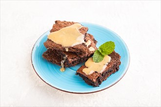 Chocolate brownie with caramel sauce on gray concrete background. side view, close up
