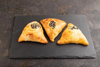 Homemade asian pastry samosa on black concrete background. side view