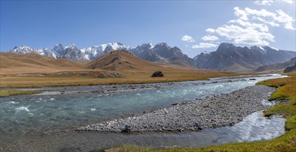 Mountain landscape with yellow meadows and river Kol Suu, mountain peak with glacier, hike to the