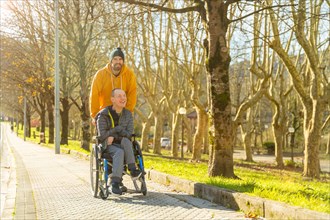 Disabled man and friend along a path in a park during a sunny day of winter