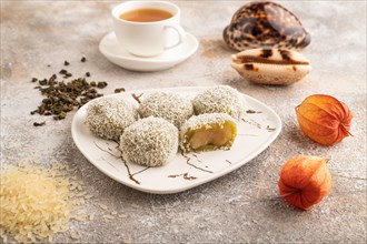 Japanese rice sweet buns mochi filled with pandan jam and cup of green tea on brown concrete