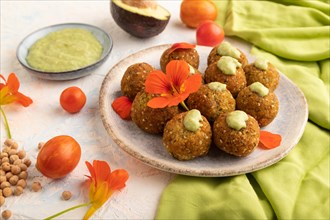 Falafel with guacamole on white concrete background and green linen textile. Side view, close up