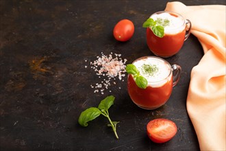 Tomato juice with basil, himalayan salt and sour cream in glass on a black concrete background with
