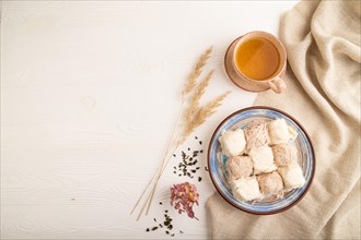 Traditional arabic sweets pishmanie and a cup of green tea on white wooden background and linen