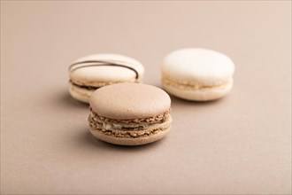 Brown and white macaroons on beige pastel background. side view, close up, still life. Breakfast,