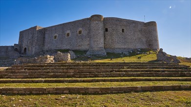 Ruins of a castle with pre-stages, surrounded by green grass, under a bright blue sky, Chlemoutsi,