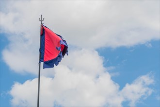 Red flag with blue fringe on metal pole under cloudy blue sky in South Korea