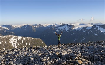 Mountain panorama with mountain peaks and Jostedalsbreen glacier, mountaineer stretches his arms in