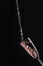 A champagne glass is filled with sparkling wine, captured against a dark backdrop