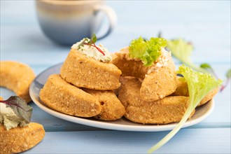 Homemade salted crescent-shaped cheese cookies, cup of coffee on blue wooden background. side view,