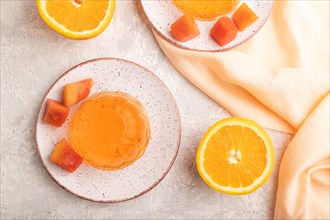 Papaya and orange jelly on gray concrete background and orange linen textile. top view, flat lay,
