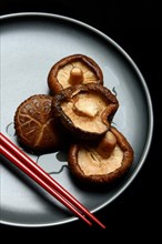 Dried and soaked shiitake mushrooms on a plate with chopsticks