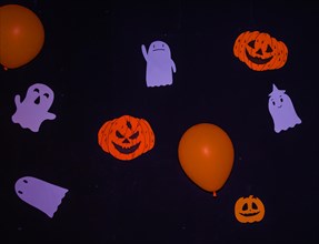 Halloween decorations of handmade ghosts, Jack-o-Lanterns, and orange balloons hanging on a black