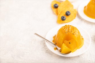 Mango and passion fruit jelly with blueberry on gray concrete background and linen textile. side