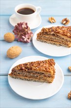 Walnut and hazelnut cake with caramel cream, cup of coffee on blue wooden background. side view,