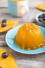 Mango and passion fruit jelly with blueberry on gray wooden background. side view, close up,