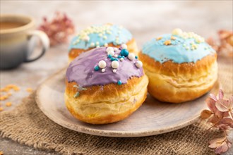 Purple and blue glazed donut and cup of coffee on brown concrete background and linen textile. side