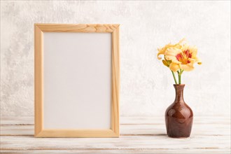 Wooden frame with orange day-lily flowers in ceramic vase on gray concrete background. side view,