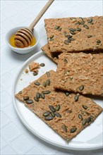 Crispbread with seeds and bowls of honey