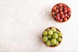Fresh red and green gooseberry in clay bowl on gray concrete background. top view, flat lay, copy
