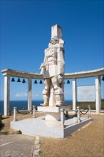 Monumental statue under a clear blue sky with a memorial plaque and bells, Memorial to Admiral