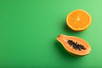 Ripe cut papaya and orange on green pastel background. Side view, copy space. Tropical, healthy