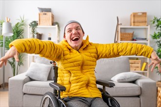 Portrait of a happy moment of a cheerful disabled man in wheelchair laughing at camera at home