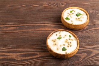 Yoghurt with granadilla and mint in wooden bowl on brown wooden background. side view, copy space