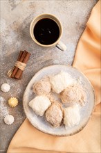 Traditional arabic sweets pishmanie and a cup of coffee on brown concrete background and orange