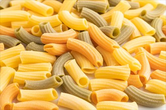 Rigatoni colored raw pasta, texture, background. Side view