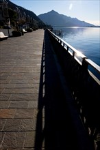 Shadow of a Railing on the Street on the Waterfront to Lake Ceresio in Campione d'Italia, Lombardy,