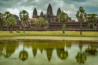 Angkor Wat temple complex in Cambodia with its reflection on water under a cloudy sky. Siem reap,